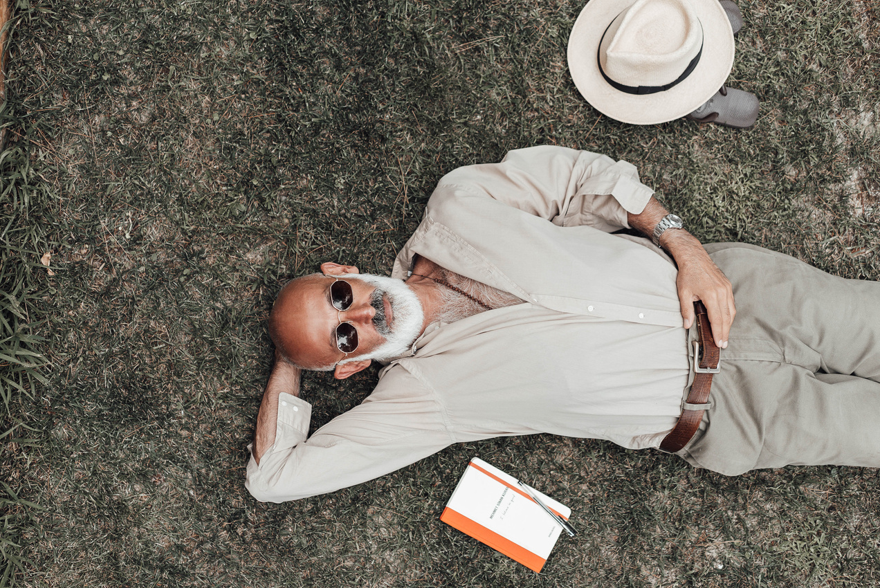 Stylish mature man resting on grass